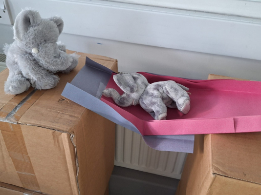 A unstable paper bridge across the gap between two boxes collapsing as a toy elephant is placed on it.