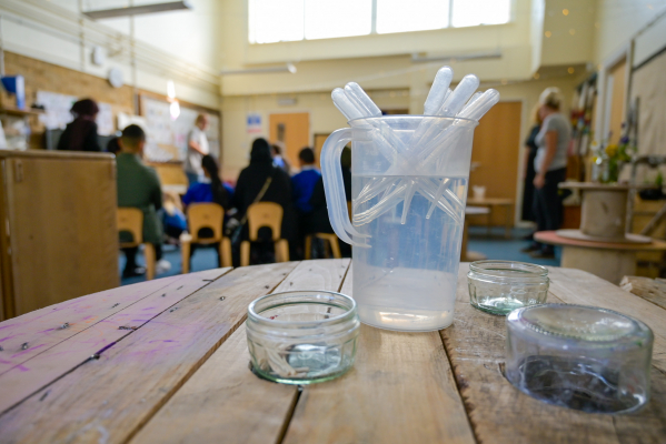 Pipettes in jug of water set out on a table to use.