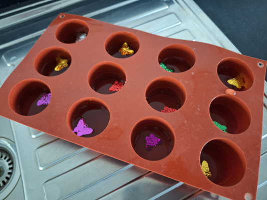 Ice cube tray where each section contains 1cm of water and a small floating craft shape.