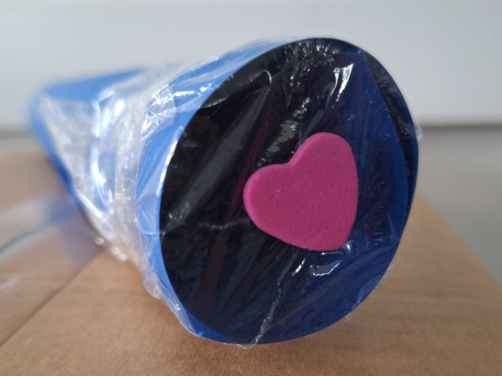 A cardboard tube with cellophane covering one end and a sticker in the centre of the cellophane.